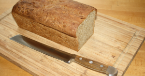 Bread knife and pan loaf on wooden cutting board
